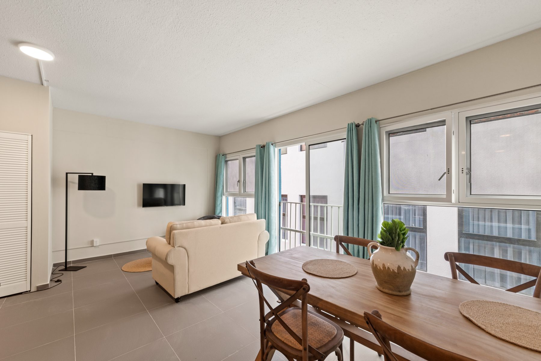 The Quarter: bright street-level living and dining room with turquoise curtains