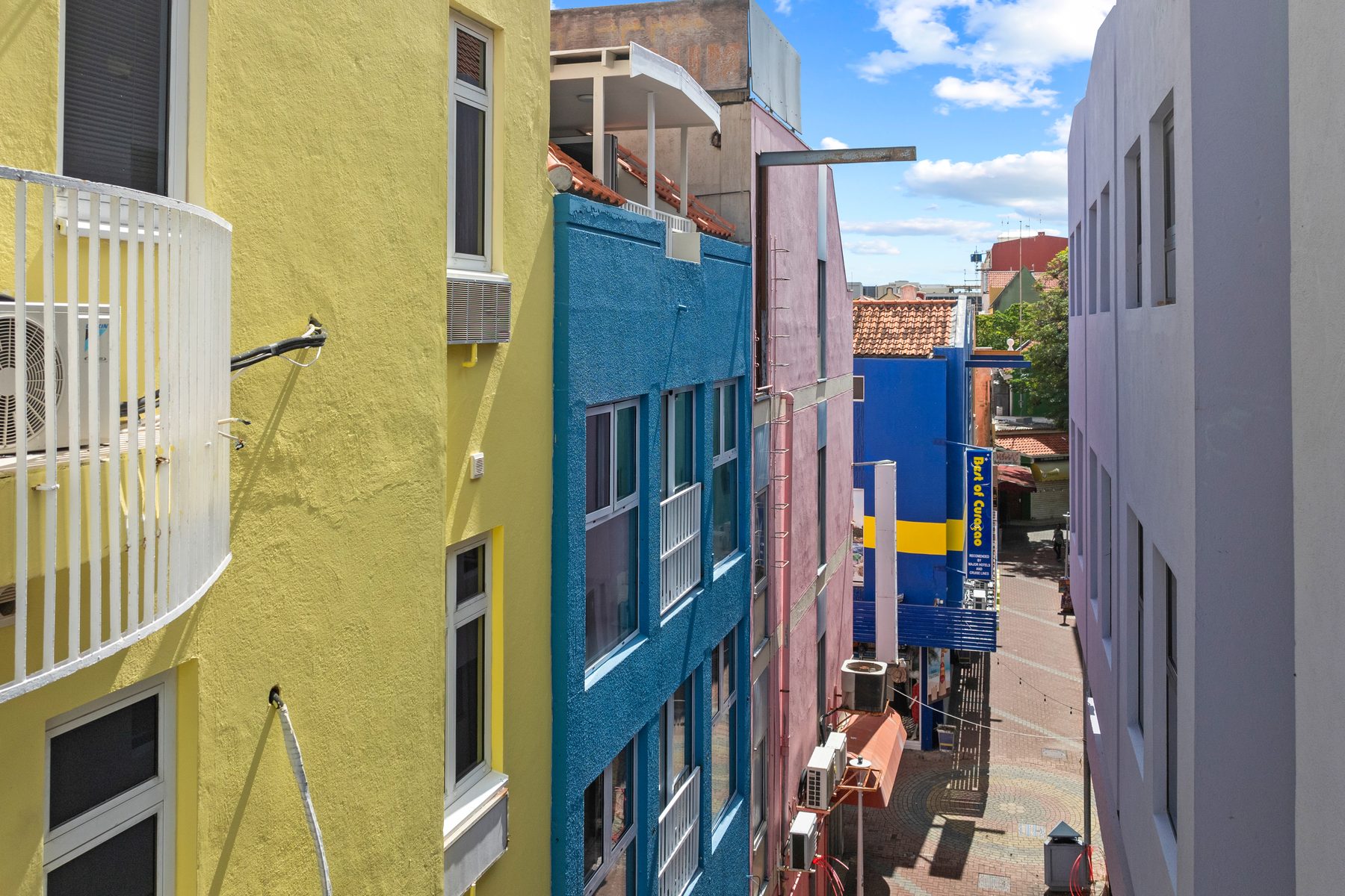A colourful Willemstad lane of yellow, blue and pink facades running down to the harbour