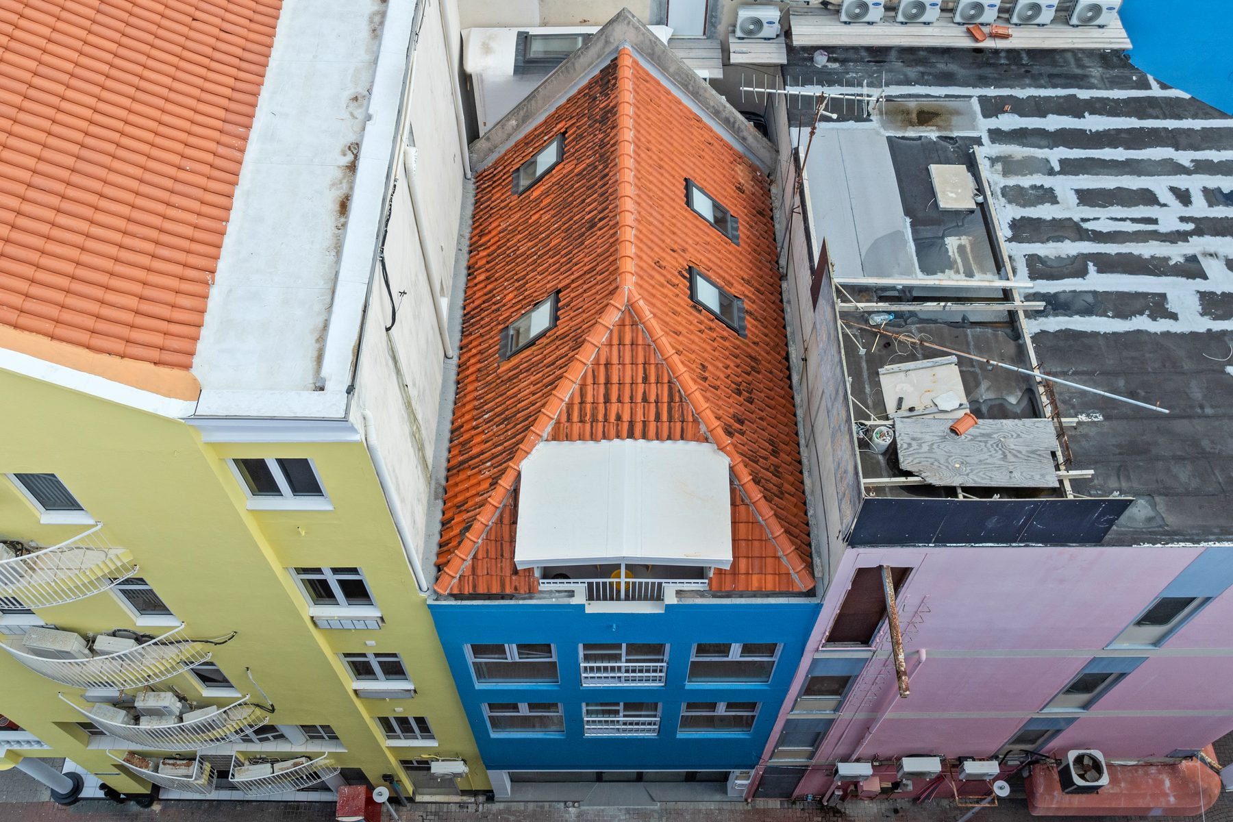 Aerial view of the blue townhouse with its orange-tiled roof and rooftop terrace in the old town of Willemstad